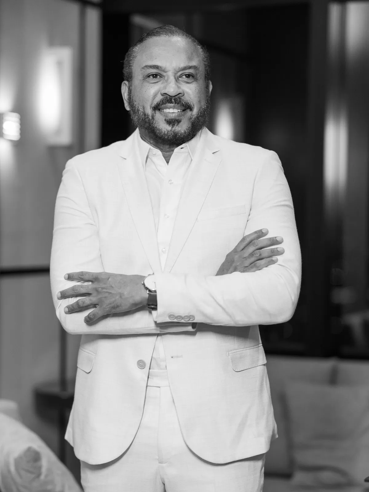 Dr. Ribamar Cruz de terno claro e braços cruzados, sorrindo, em foto preto e branco.